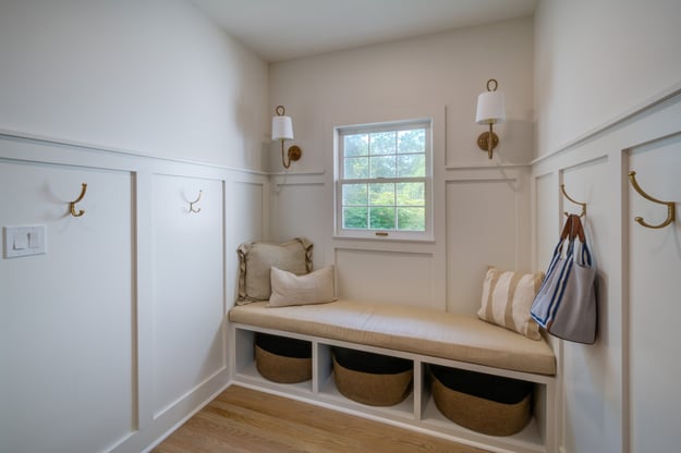 Custom mudroom with bench with storage, seating, sconces, and hooks