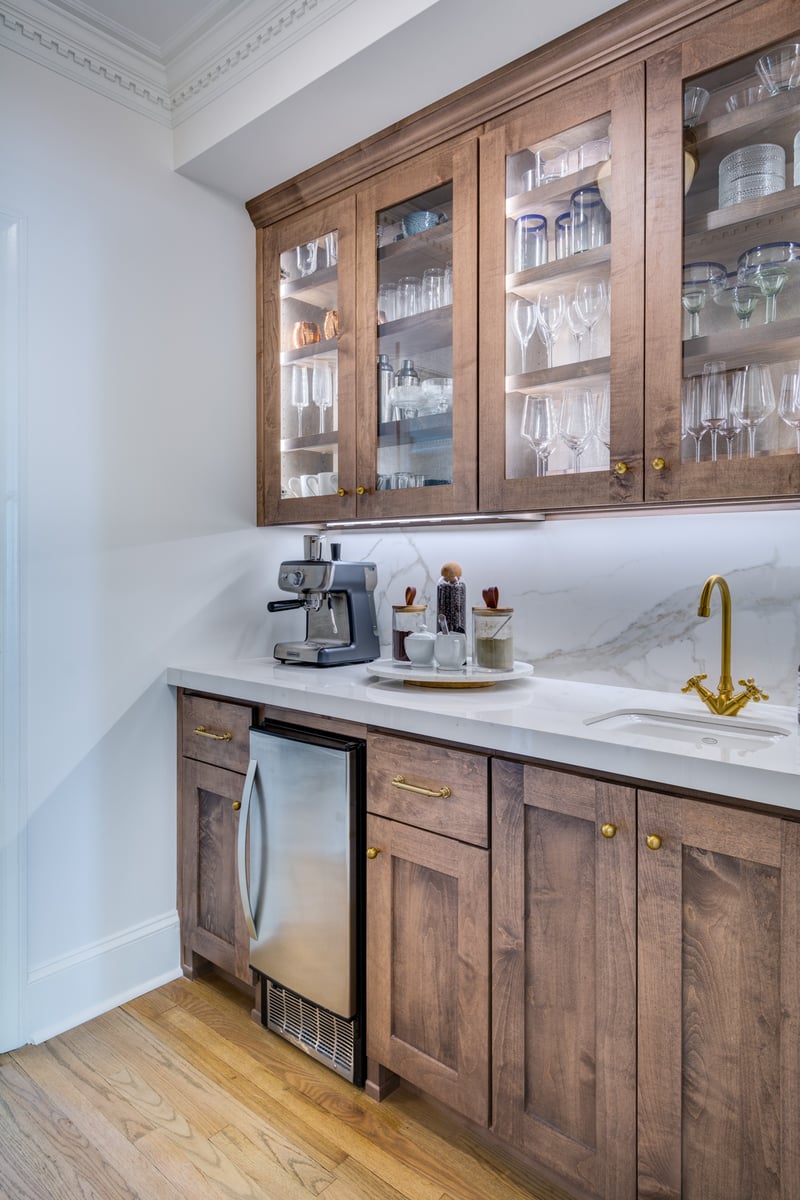 beverage station in Atlanta kitchen remodel with custom lit glass front walnut cabinets and slab backsplash