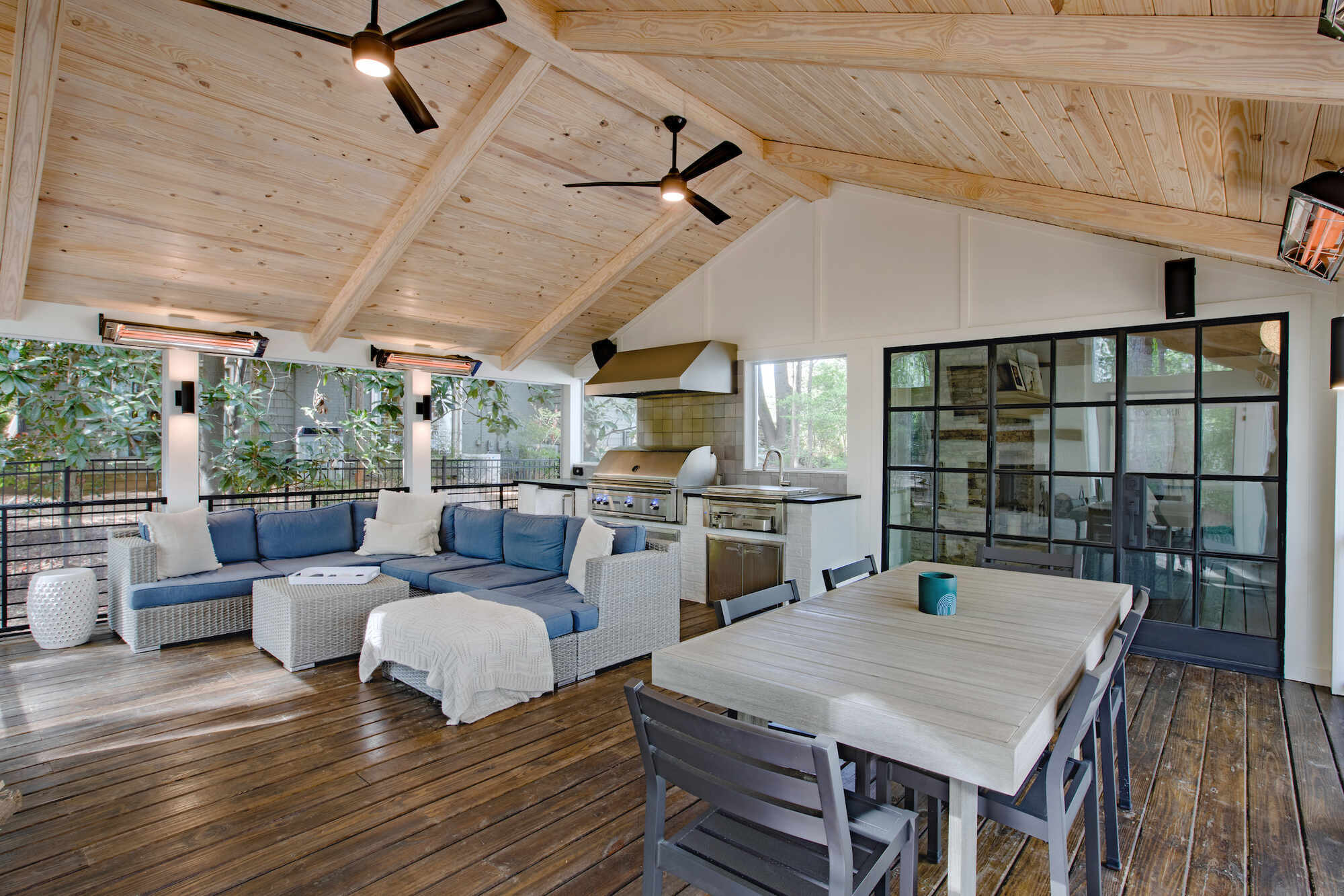 Covered outdoor kitchen and lounge area with wood ceiling and modern furniture by Silver Oak Remodel in Atlanta, GA