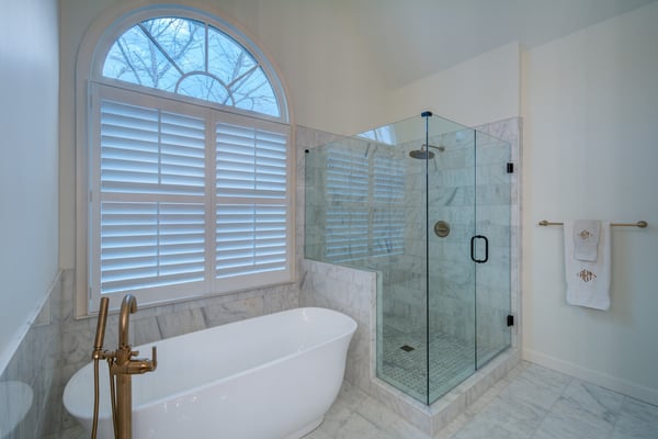 Spacious marble bathroom remodel with arched window and walk-in shower by Silver Oak Remodel in Atlanta, GA