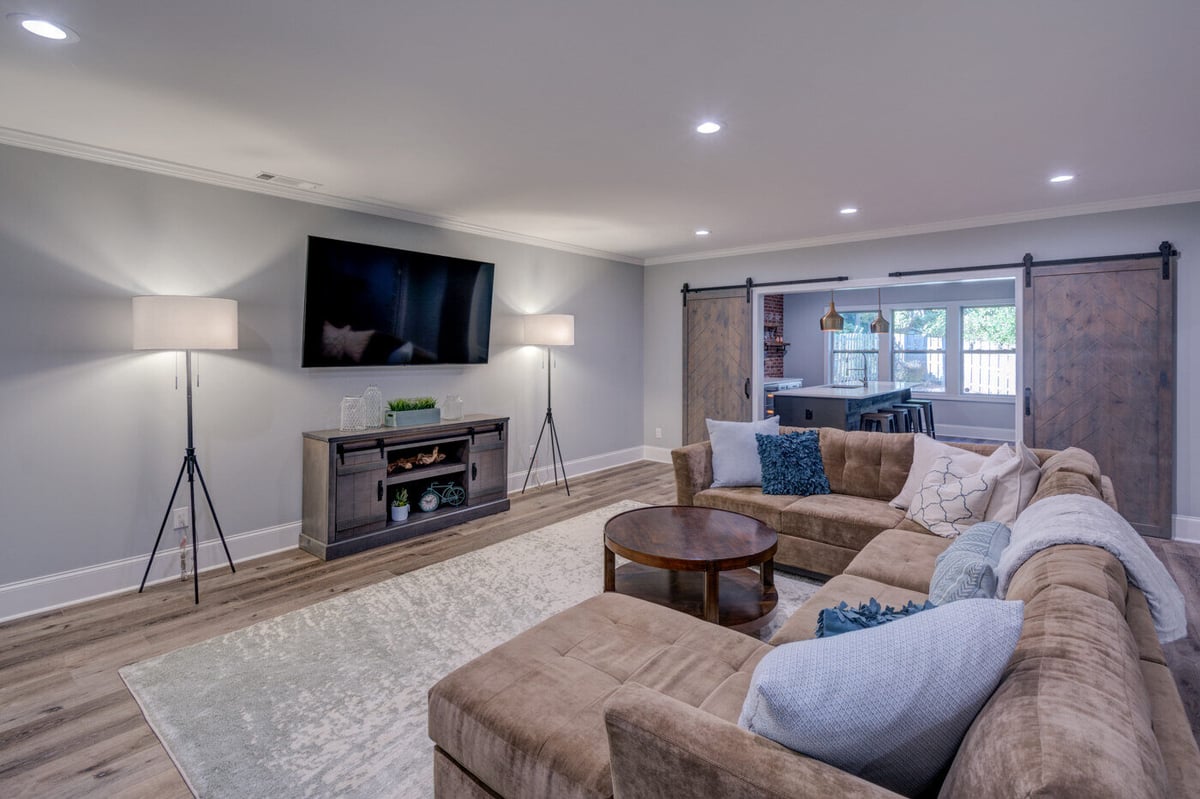 Basement living area with sectional and barn doors in Atlanta remodel by Silver Oak Remodel