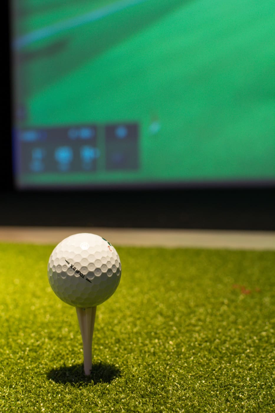 Close-up of golf ball on tee in indoor golf simulator room in Atlanta custom home by Silver Oak Remodeling