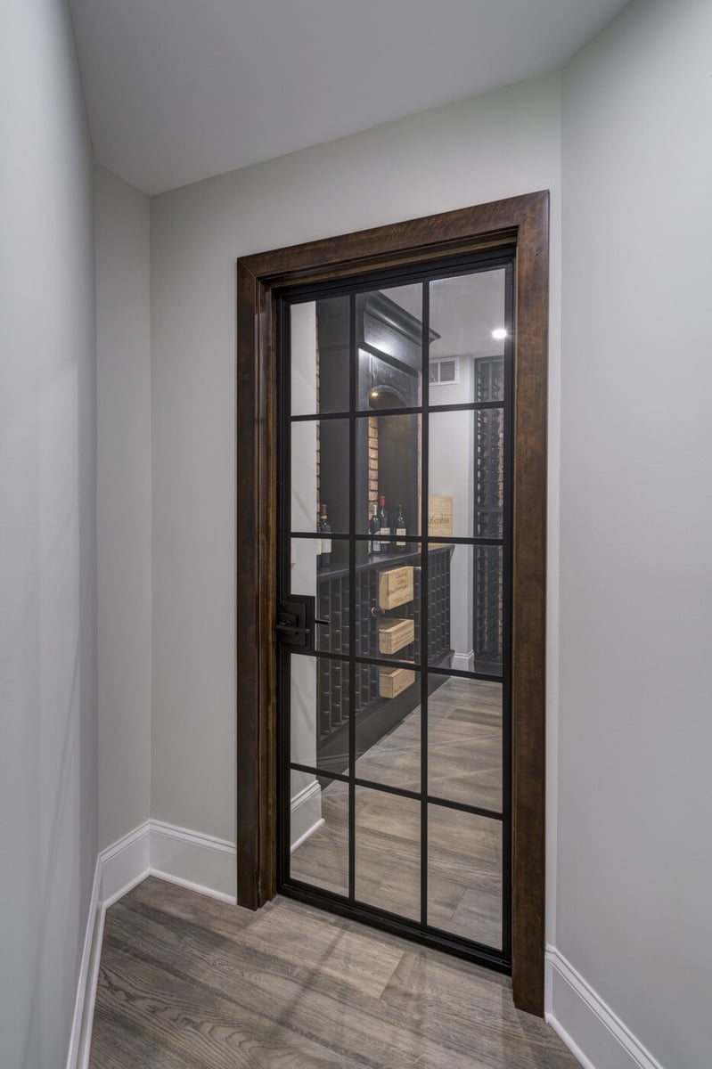 Glass-paneled door leading into custom wine room in Atlanta basement remodel by Silver Oak Remodel