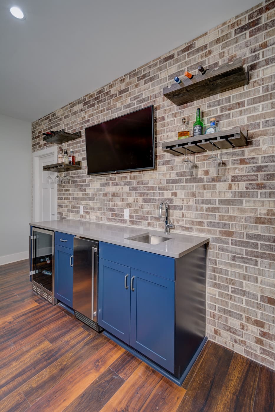 Home bar with stainless appliances and rustic brick wall in a custom-built Atlanta home by Silver Oak Remodeling