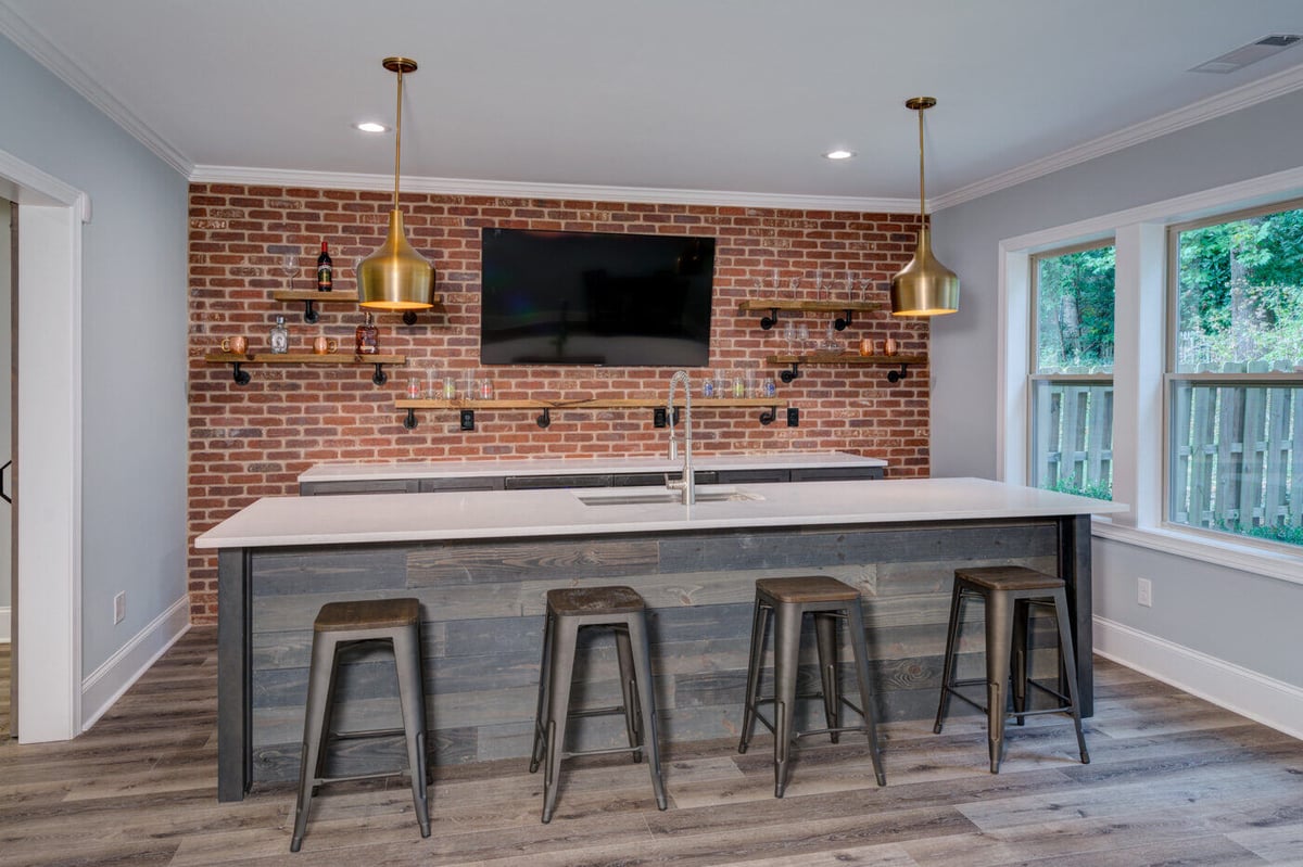 Modern basement bar with brick wall and pendant lights in Atlanta remodel by Silver Oak Remodel