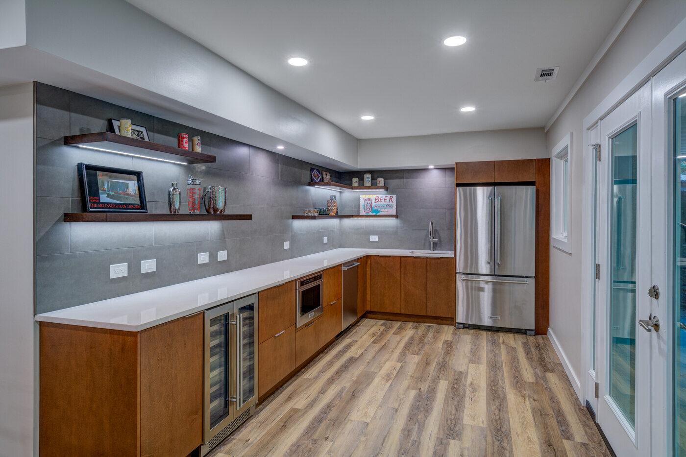 Modern basement kitchenette with floating shelves and built-in beverage cooler by Silver Oak Remodel in Atlanta, GA