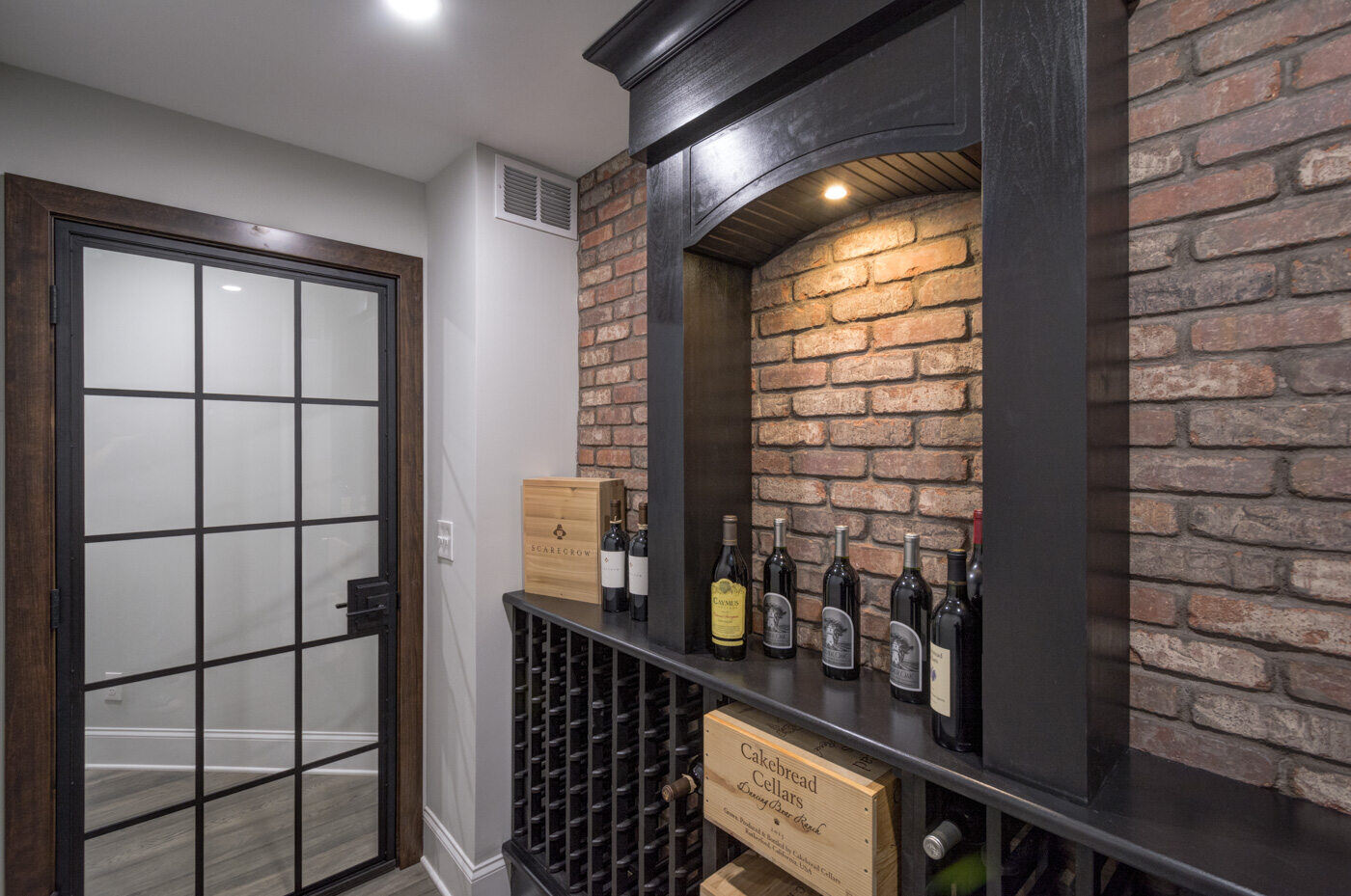 Wine cellar with exposed brick and built-in racks in Atlanta basement remodel by Silver Oak Remodel