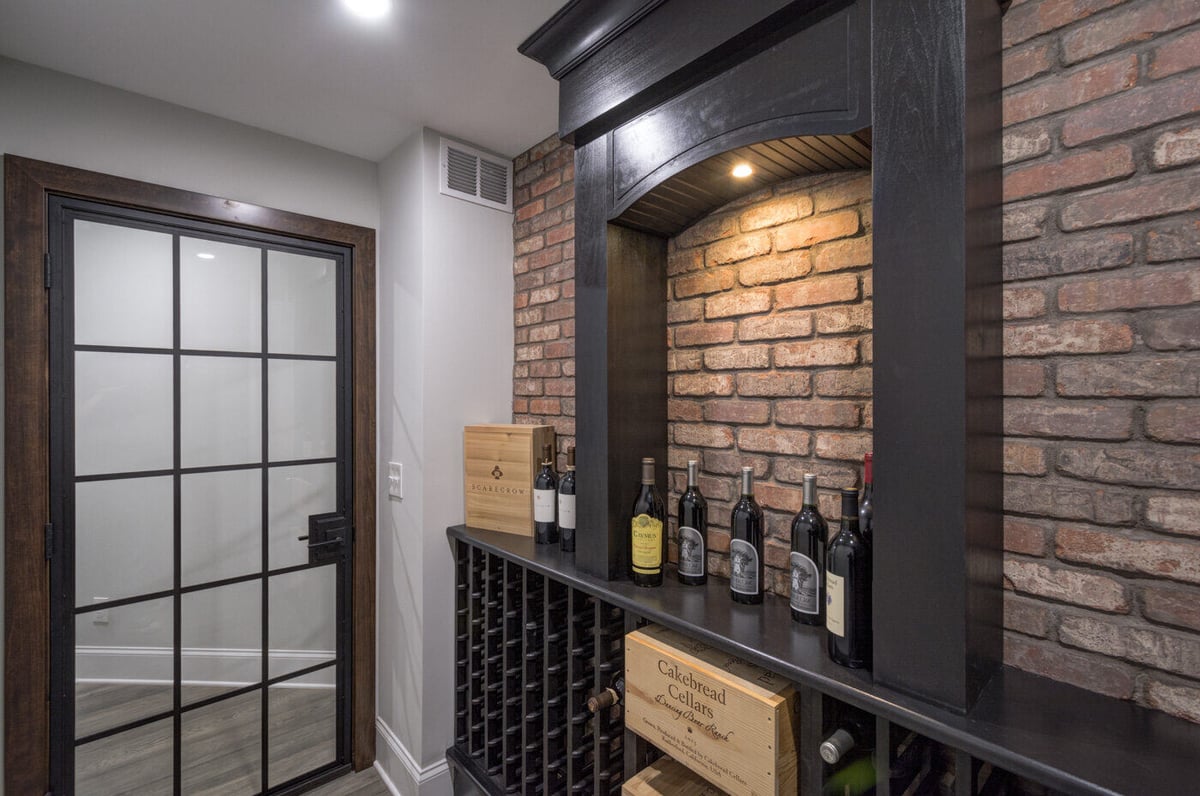Wine cellar with exposed brick and built-in racks in Atlanta basement remodel by Silver Oak Remodel