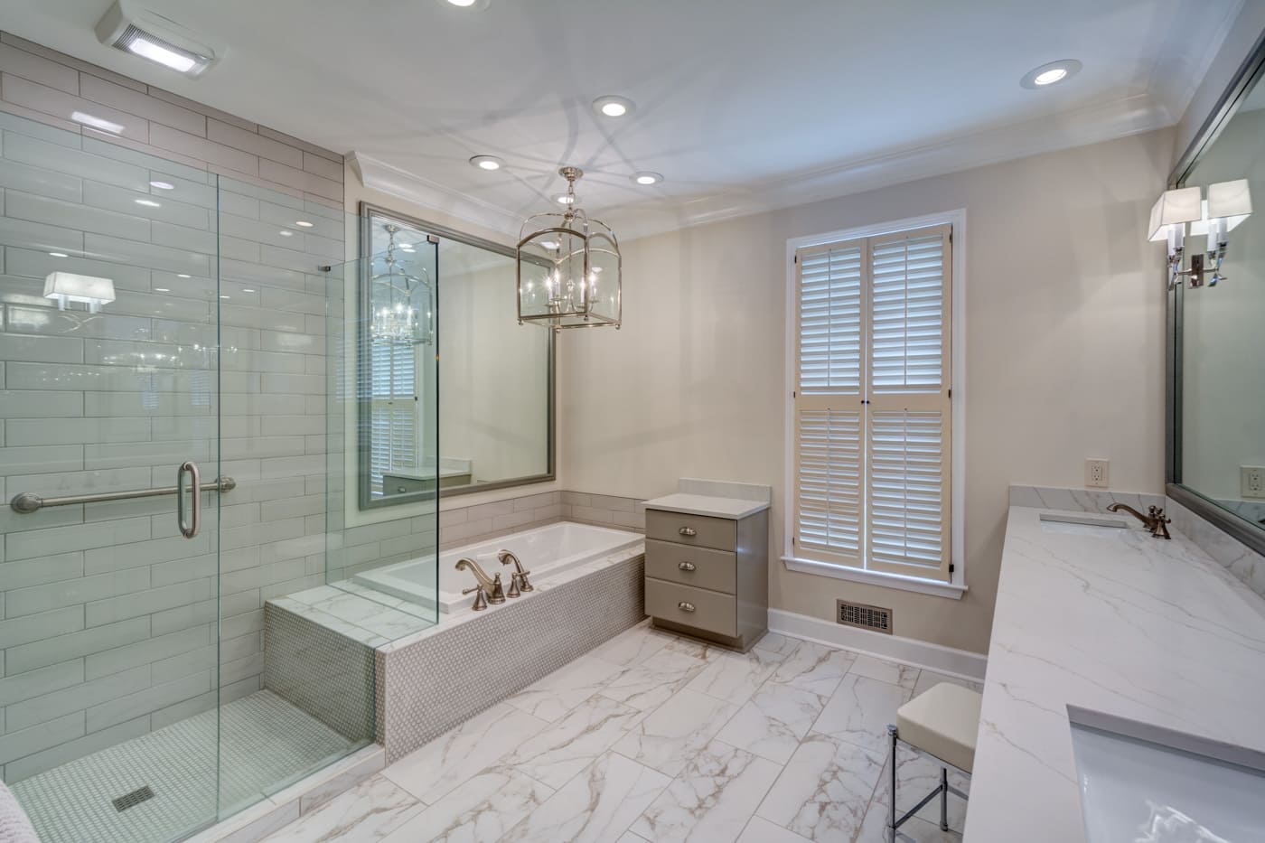 Bright primary bathroom with glass shower, soaking tub, and chandelier by Silver Oak Remodeling in Atlanta, GA