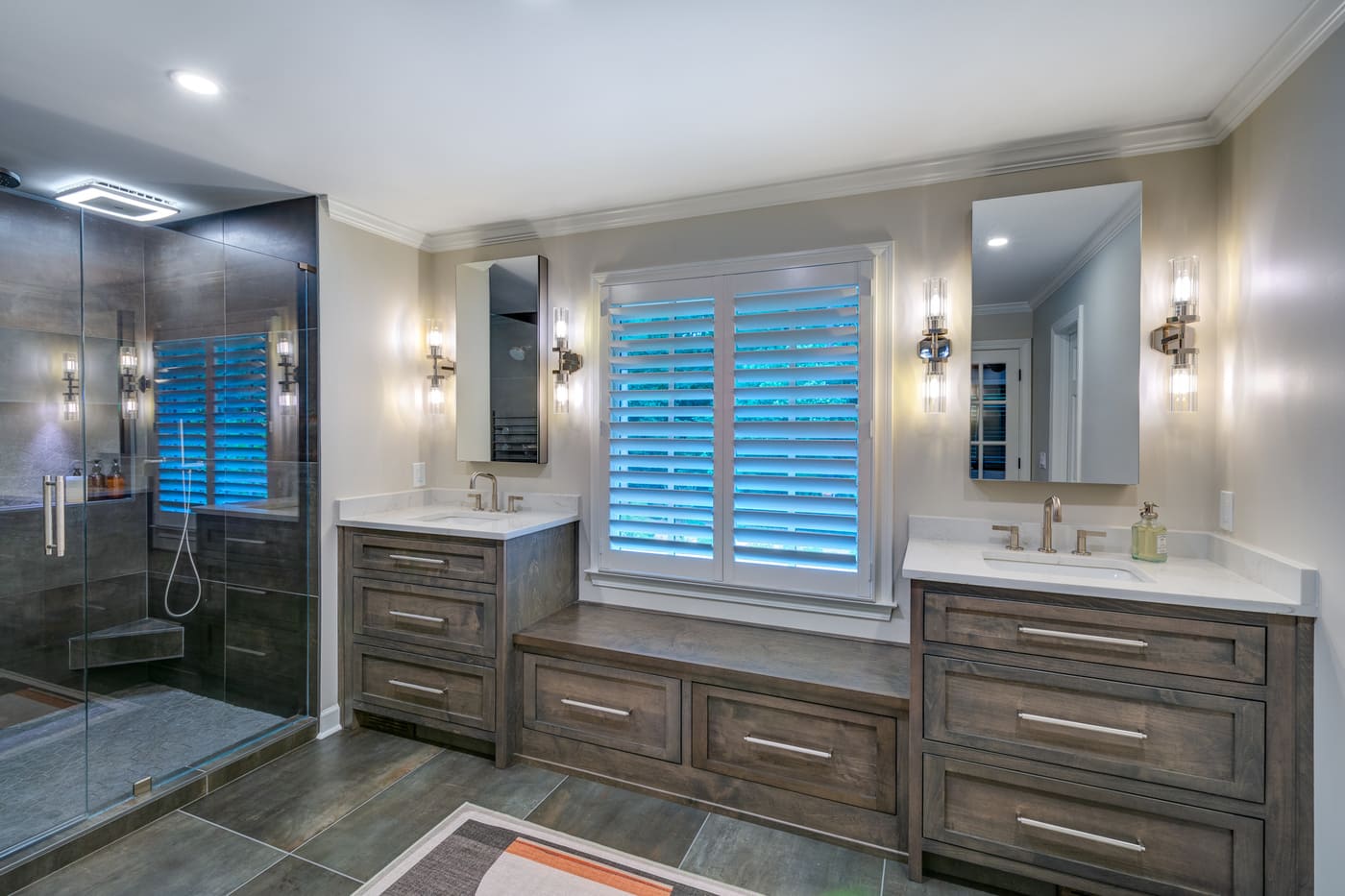 Dual vanities with built-in window bench and modern lighting in an Atlanta custom home by Silver Oak Remodeling