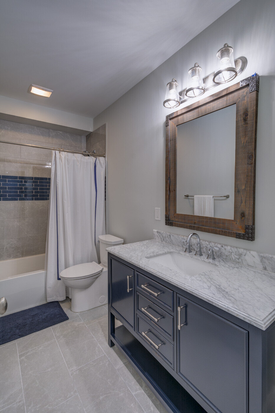 Elegant bathroom vanity with rustic wood mirror and blue cabinets by Silver Oak Remodel in Atlanta
