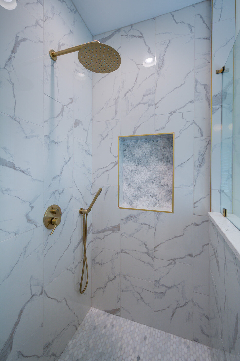 Elegant marble-tiled shower with gold fixtures by Silver Oak Remodel in an Atlanta, GA bathroom renovation