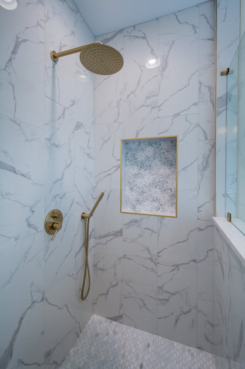 Elegant marble-tiled shower with gold fixtures by Silver Oak Remodel in an Atlanta, GA bathroom renovation