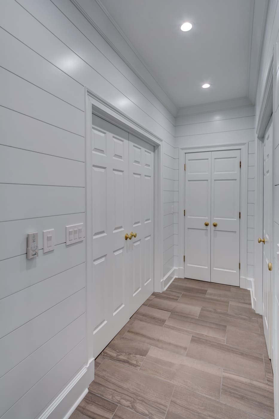 Hallway with white shiplap walls and wood-look tile flooring in a custom Atlanta home by Silver Oak Remodeling