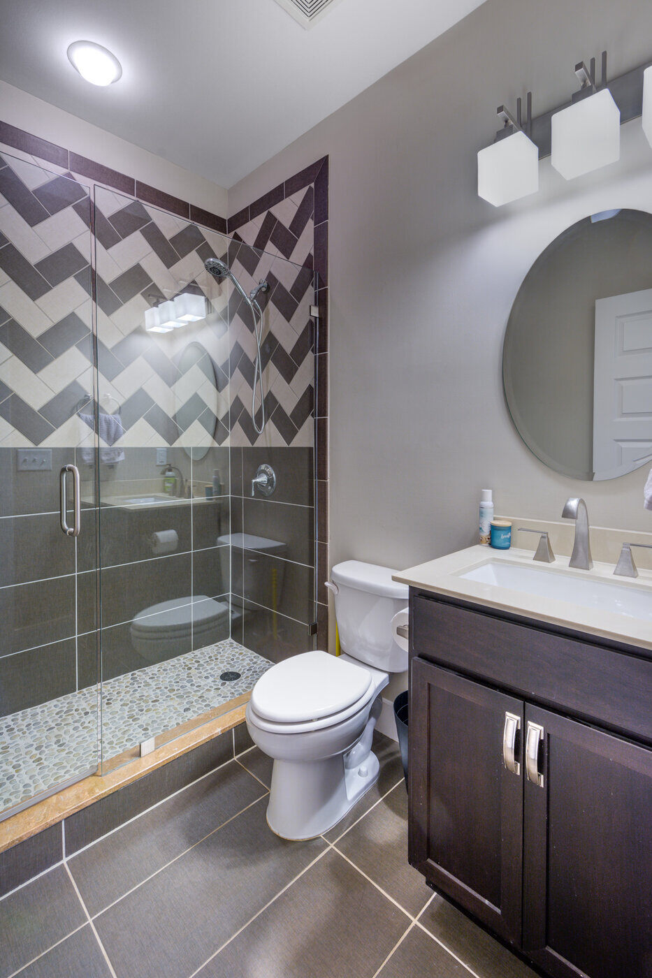 Modern glass-enclosed shower with dark chevron tile in a Silver Oak Remodel bathroom renovation in Atlanta, GA