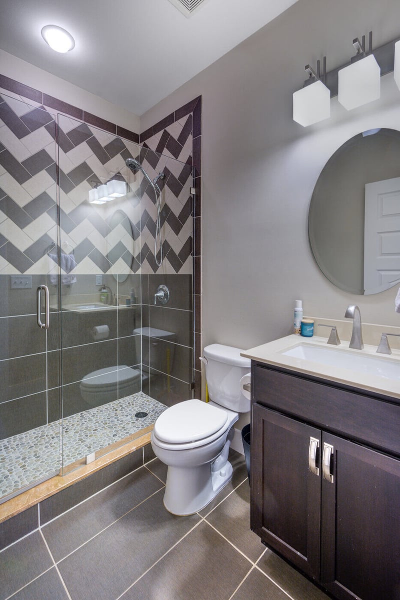 Modern glass-enclosed shower with dark chevron tile in a Silver Oak Remodel bathroom renovation in Atlanta, GA