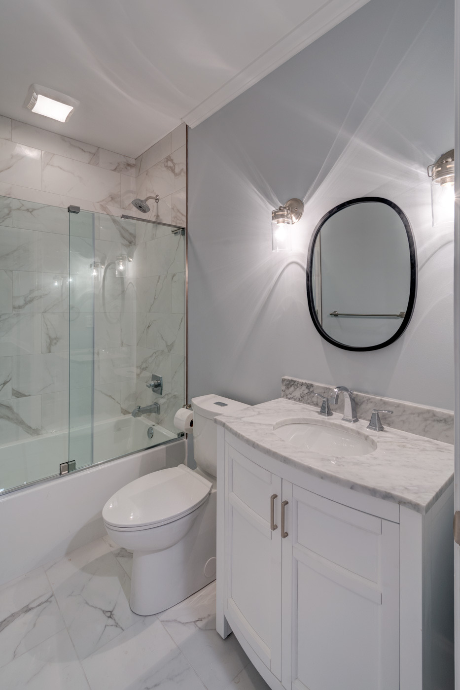 Modern guest bathroom with marble vanity and tiled shower by Silver Oak Remodel in Atlanta, GA