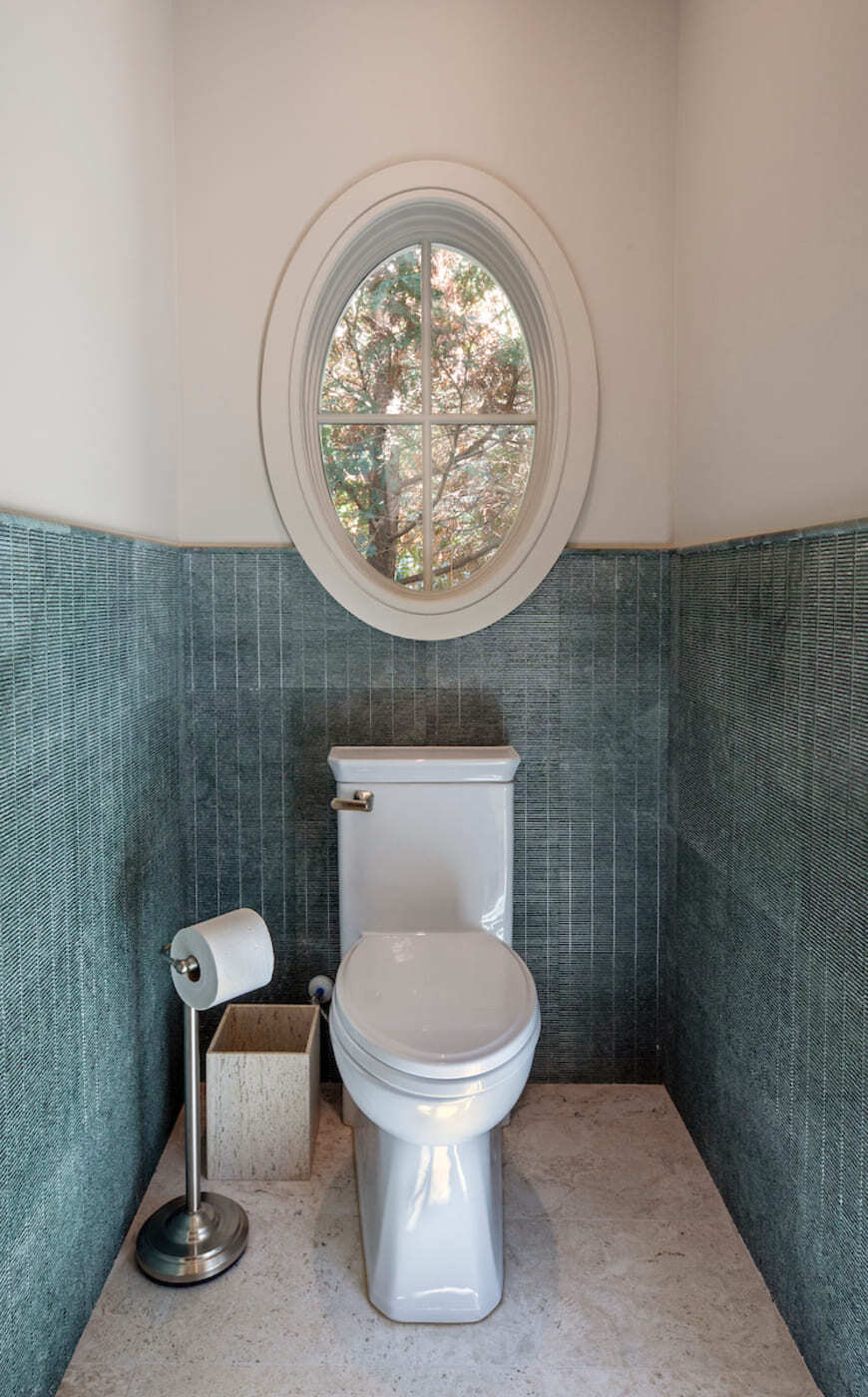Powder room with vertical teal tile and oval window in a custom home build by Silver Oak Remodeling in Atlanta, GA