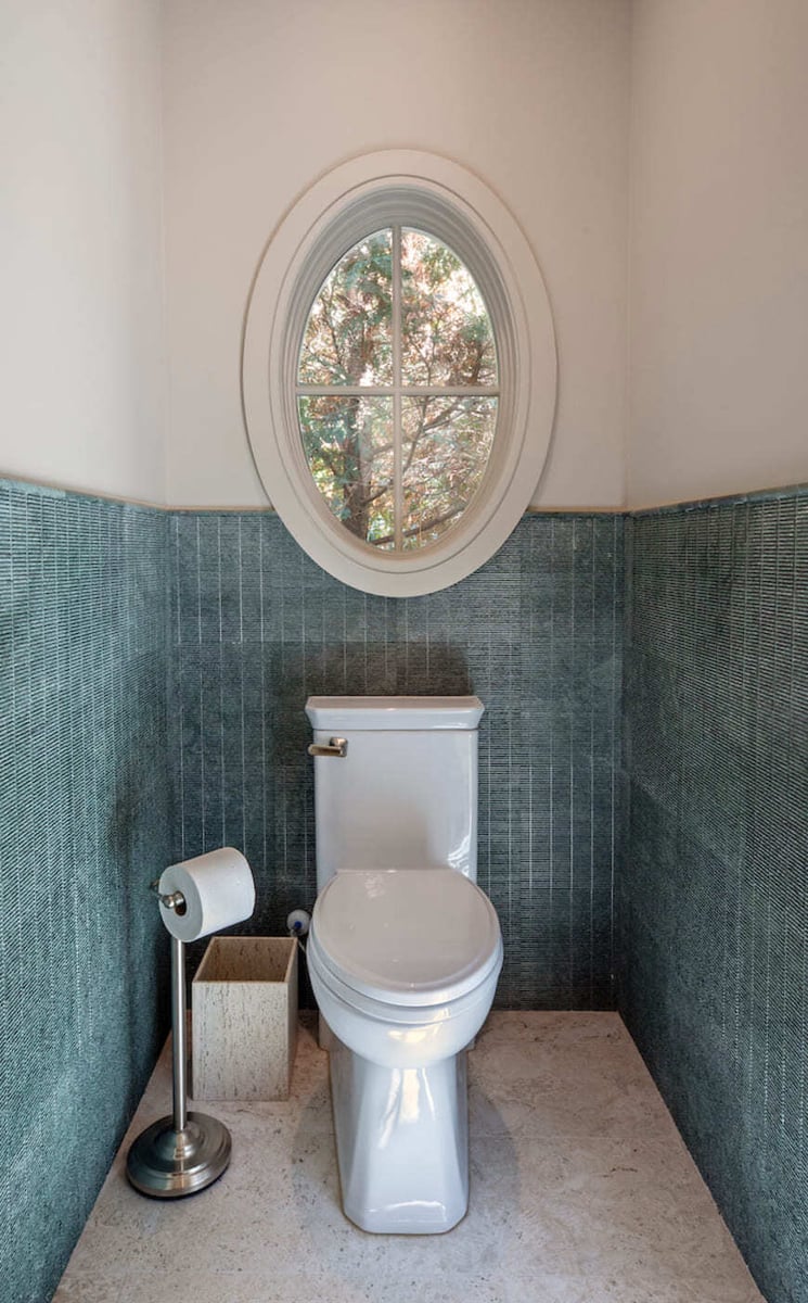 Powder room with vertical teal tile and oval window in a custom home build by Silver Oak Remodeling in Atlanta, GA