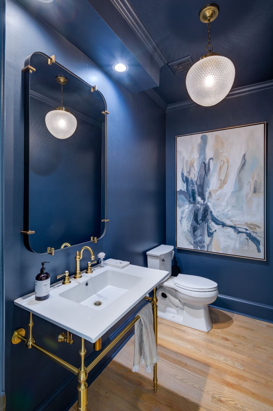 Elegant dark blue bathroom with brass accents and stylish lighting by Silver Oak Remodeling in Atlanta