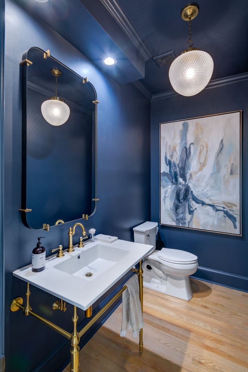 Elegant dark blue bathroom with brass accents and stylish lighting by Silver Oak Remodeling in Atlanta