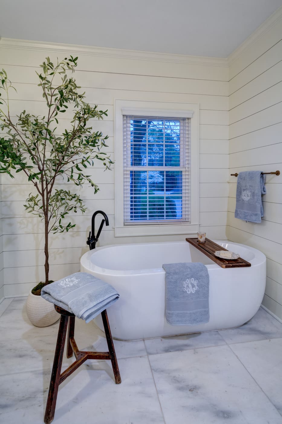 Elegant freestanding tub next to a window with tree decor in an Atlanta bathroom by Silver Oak Remodeling