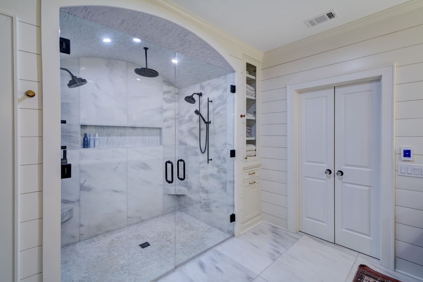 Large glass-enclosed shower with marble walls in an Atlanta custom bathroom by Silver Oak Remodeling