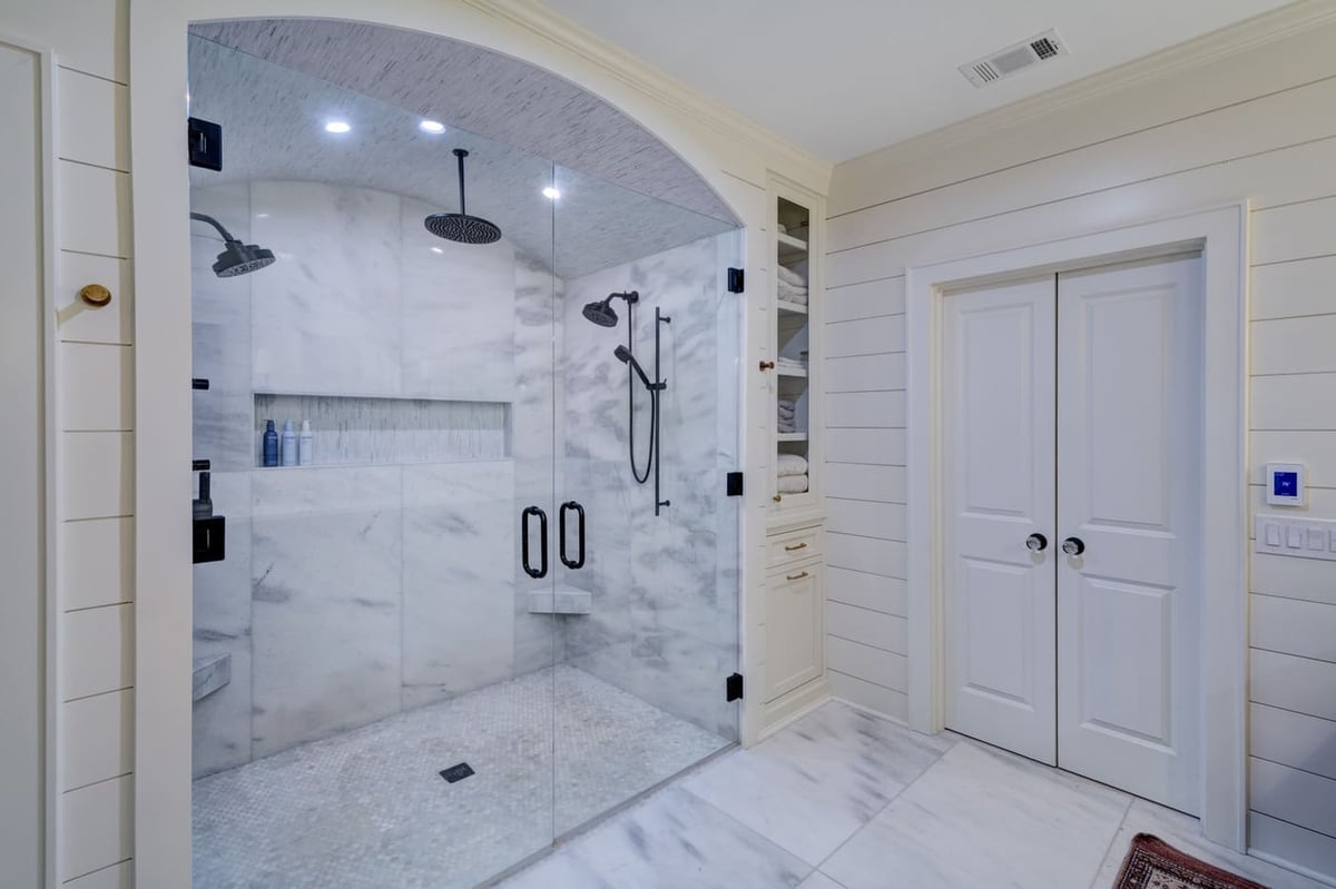 Large glass-enclosed shower with marble walls in an Atlanta custom bathroom by Silver Oak Remodeling