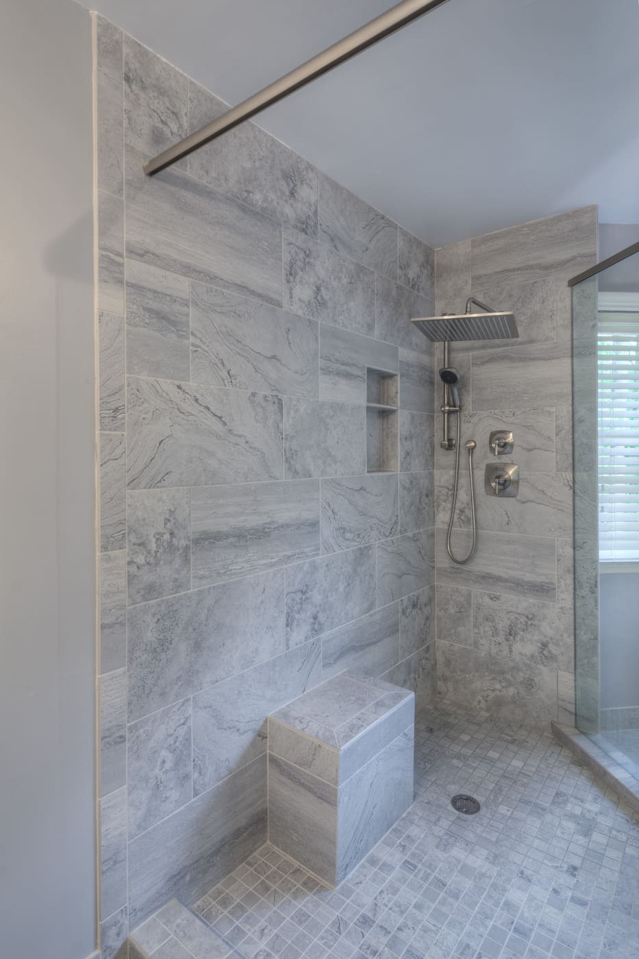 Spacious tiled shower with rainfall head and handheld sprayer, part of a Silver Oak Remodeling project in Atlanta