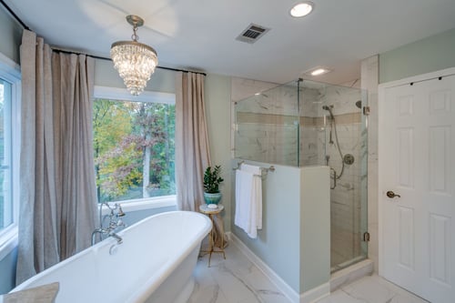 Transitional bathroom with freestanding tub, marble tile, and natural light in an Atlanta custom home by Silver Oak