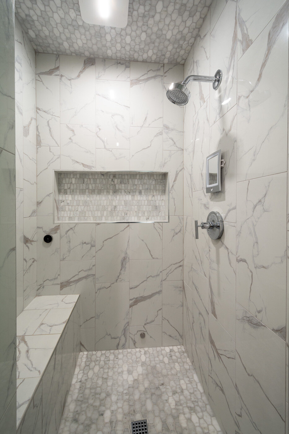 Walk-in marble tile shower with niche and bench by Silver Oak Remodel in Atlanta, GA