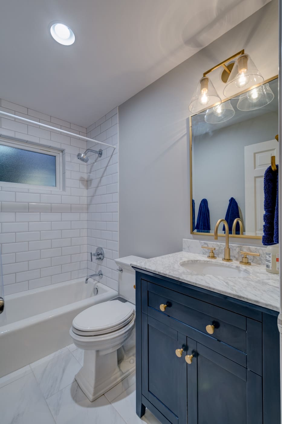 White tile shower and brass fixtures highlight this Atlanta bathroom renovation by Silver Oak Remodeling