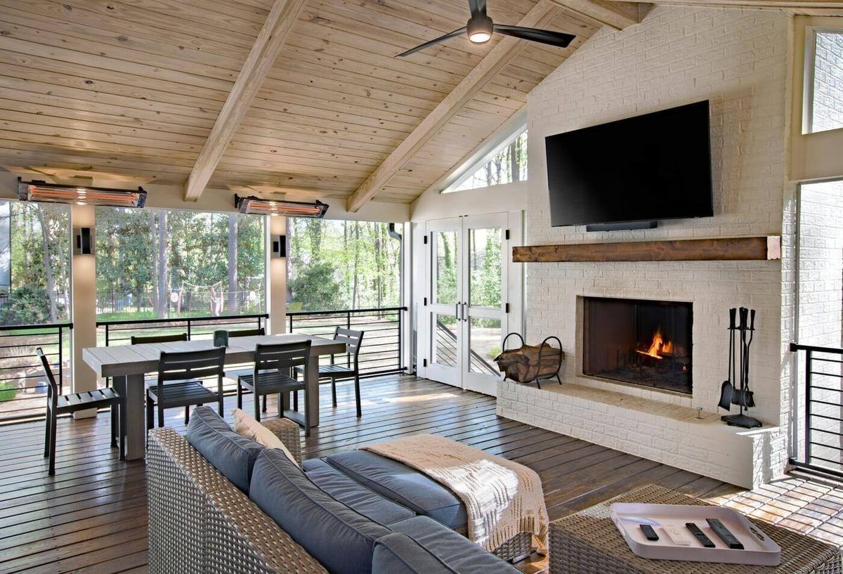 Fireplace-centered screened porch with white brick and vaulted ceiling in Atlanta, GA by Silver Oak Remodel