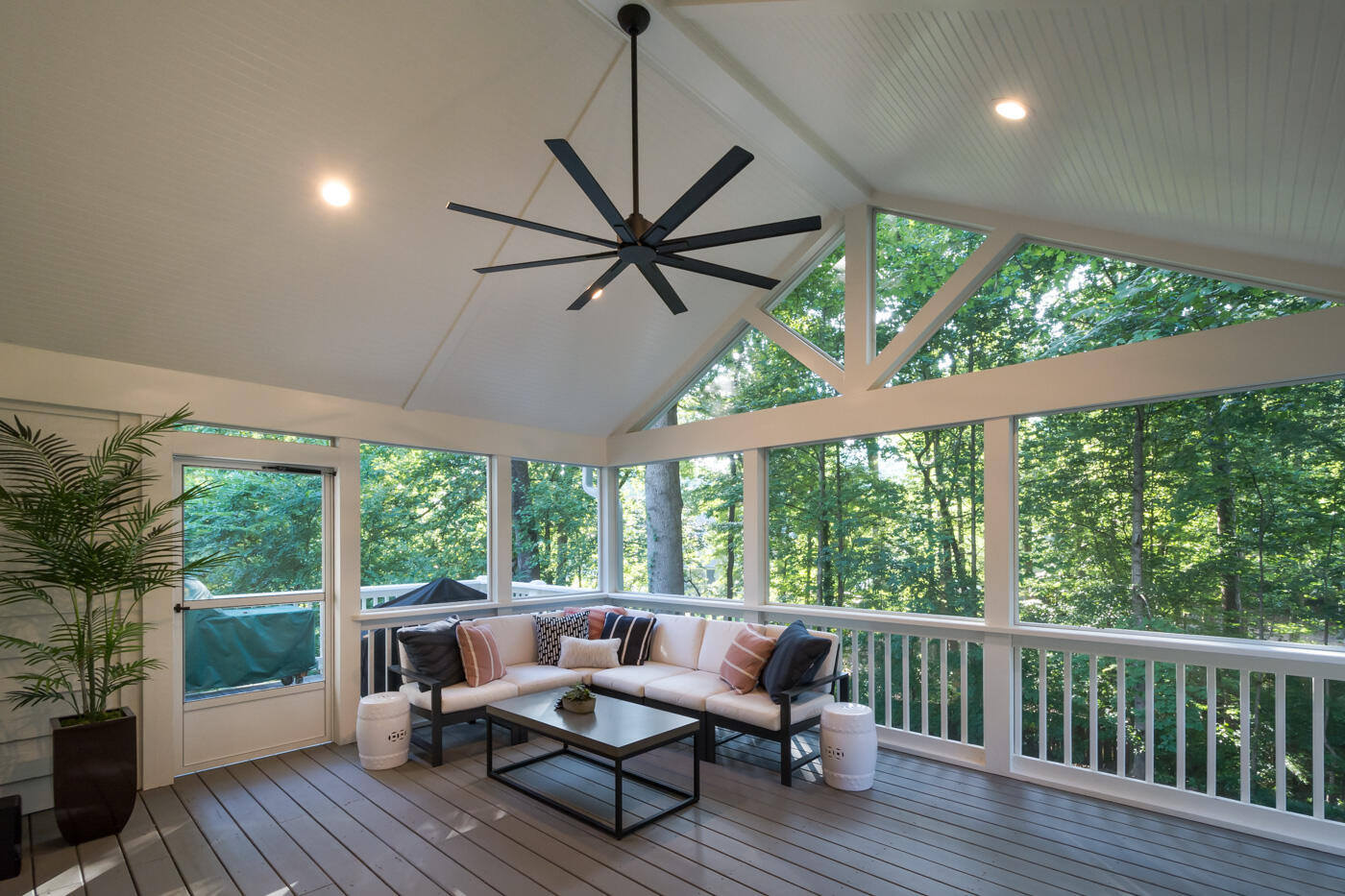 Modern screened porch surrounded by trees with vaulted ceiling and black fan by Silver Oak Remodel in Atlanta, GA