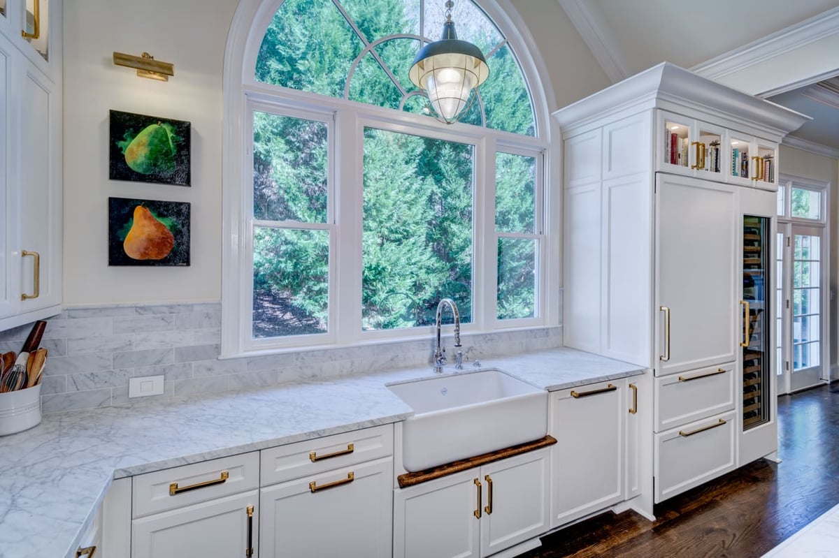 Kitchen design with marble backsplash and statement window in custom Atlanta home by Silver Oak Remodeling
