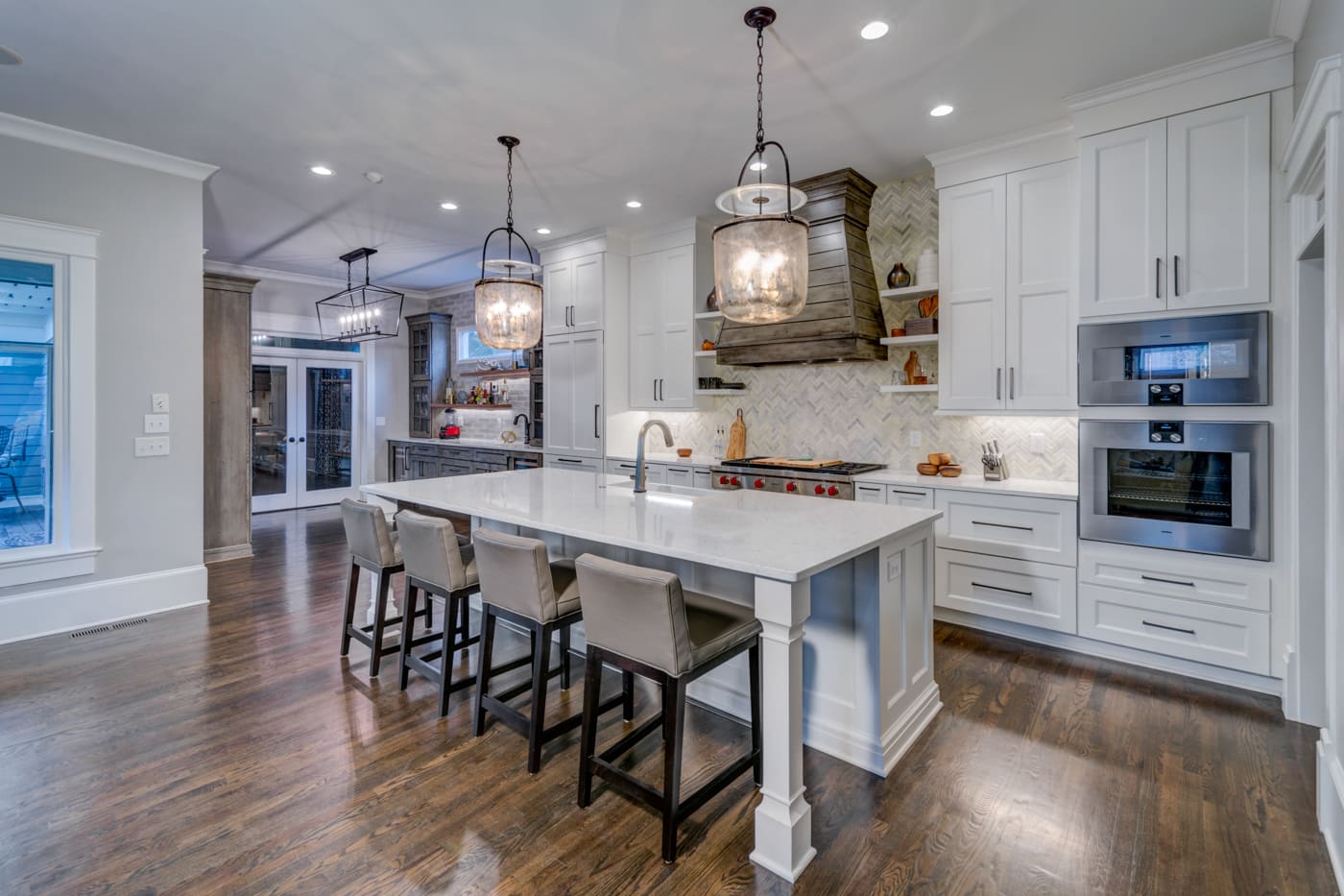 Large custom kitchen island with pendant lights and white cabinetry in Atlanta, GA by Silver Oak Remodeling