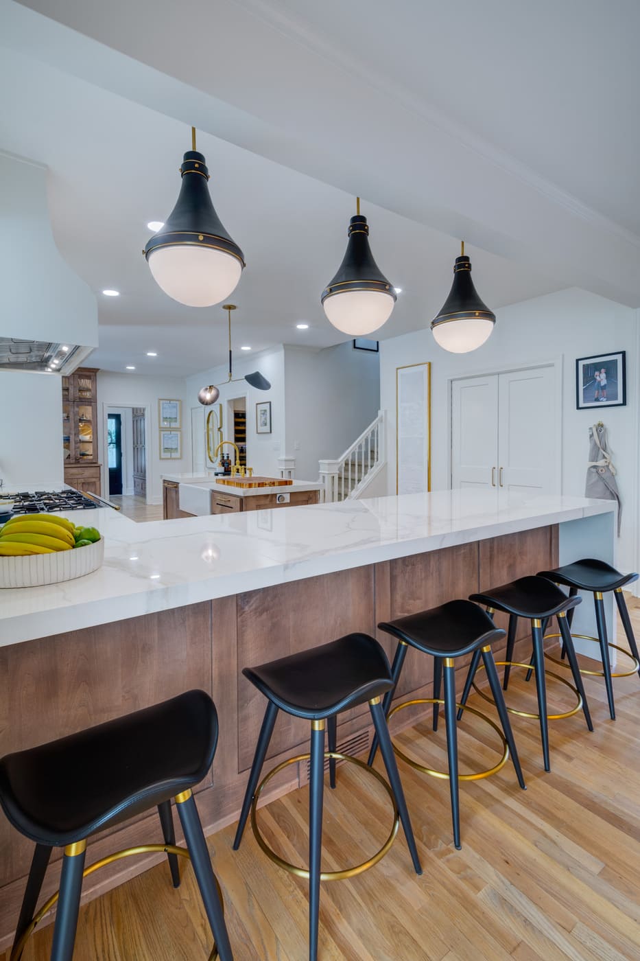 Marble waterfall island with wood paneling and black bar stools in Atlanta kitchen by Silver Oak Remodeling