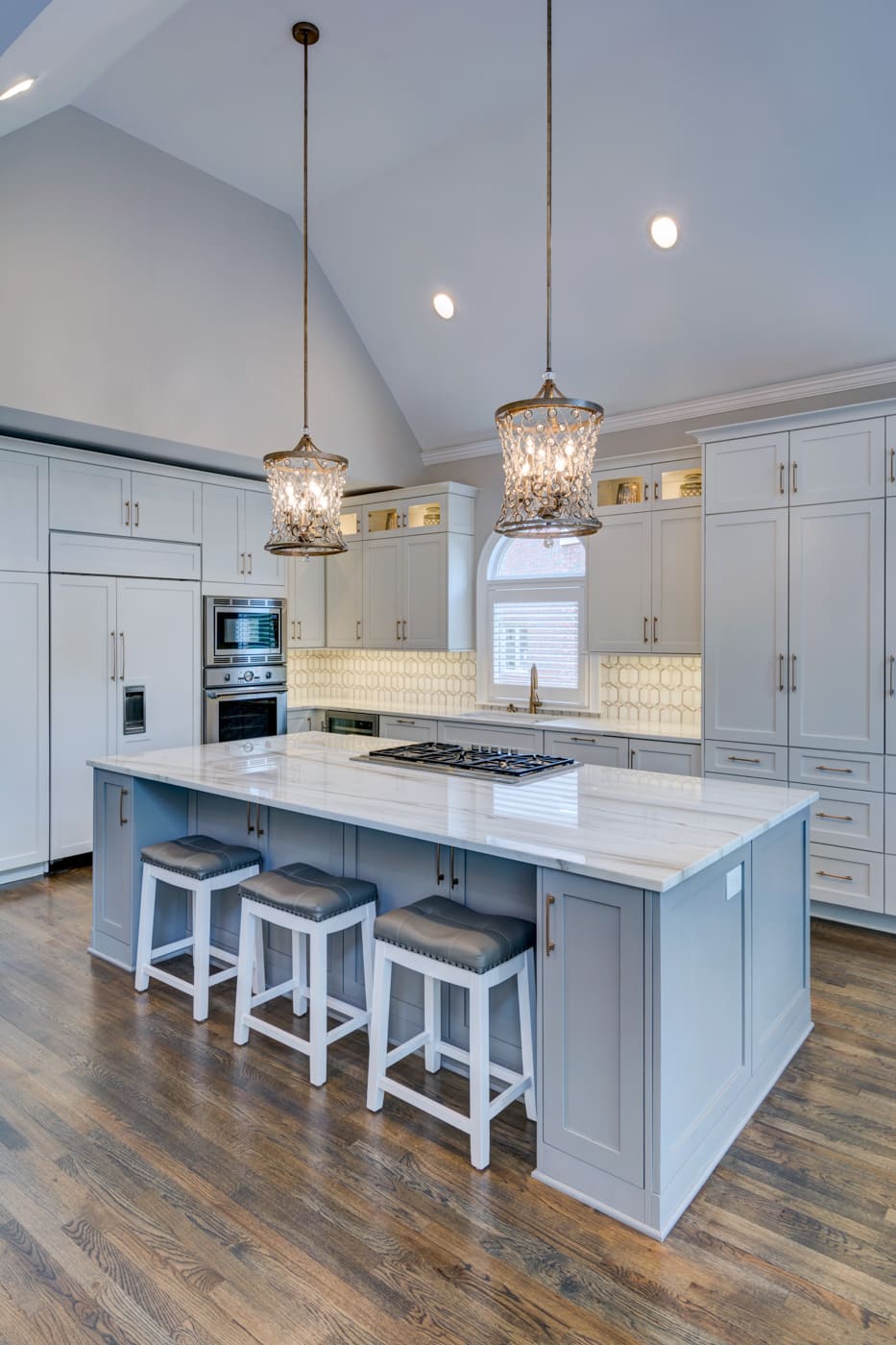 Soft blue kitchen island with quartz top and crystal chandeliers in Atlanta home by Silver Oak Remodeling
