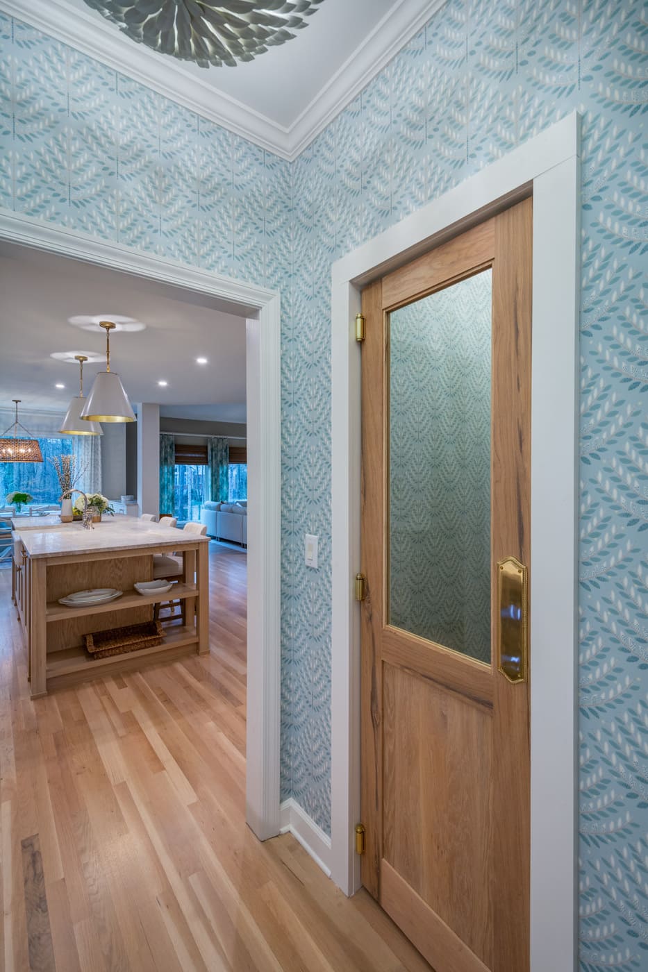 Transitional kitchen entrance with natural wood door and statement ceiling light by Silver Oak Remodeling in Atlanta