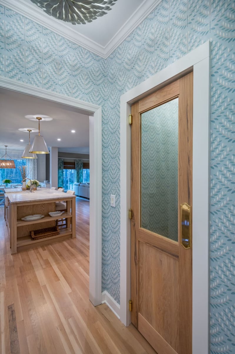 Transitional kitchen entrance with natural wood door and statement ceiling light by Silver Oak Remodeling in Atlanta