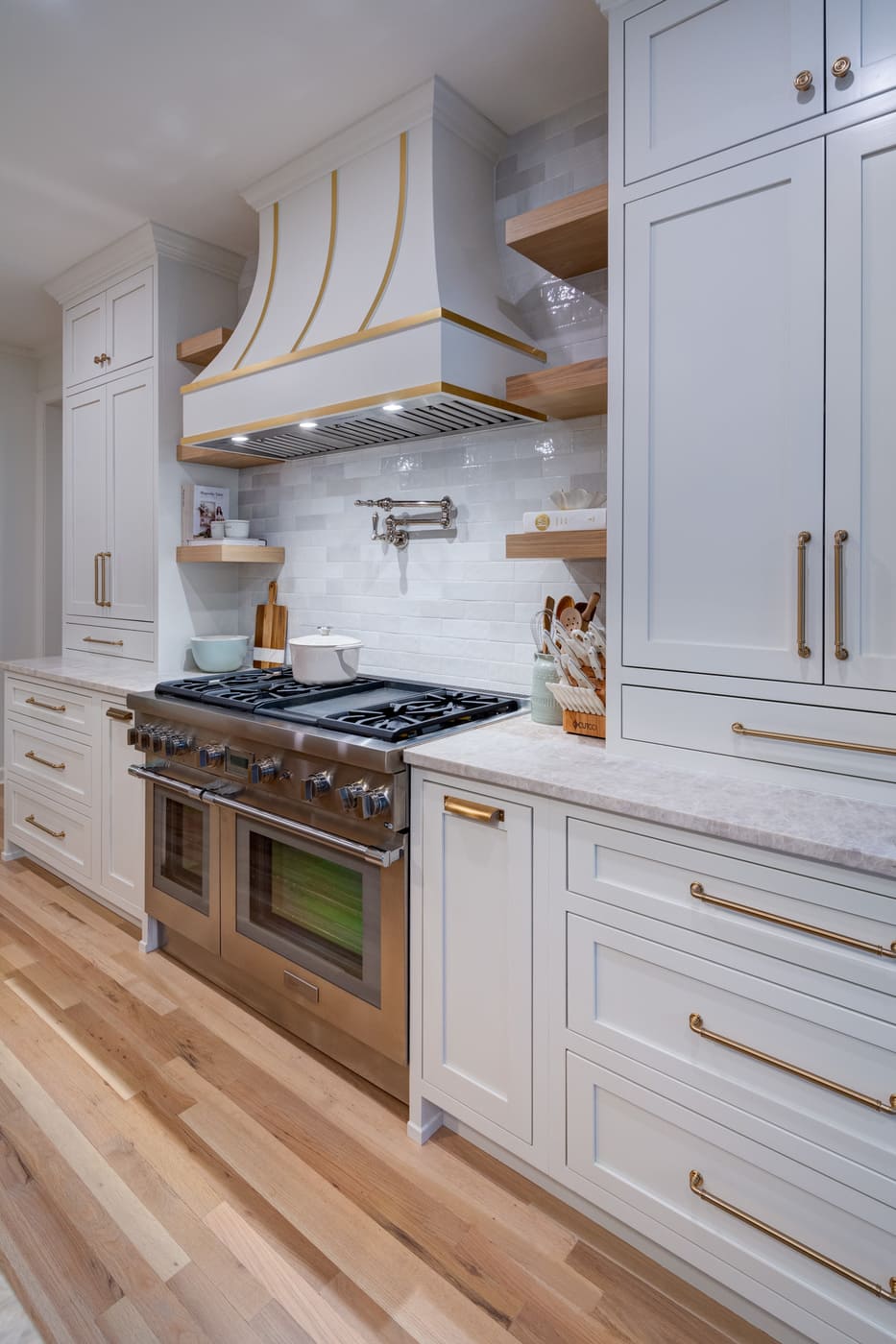White and gold kitchen hood with professional-grade stove in custom Atlanta home by Silver Oak Remodeling