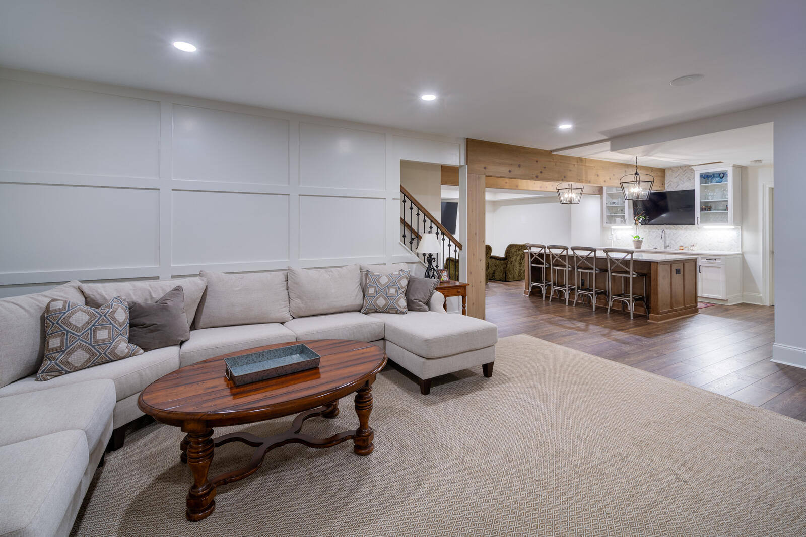 Open basement layout with kitchen and sectional seating in Roswell GA remodel by Silver Oak Remodel