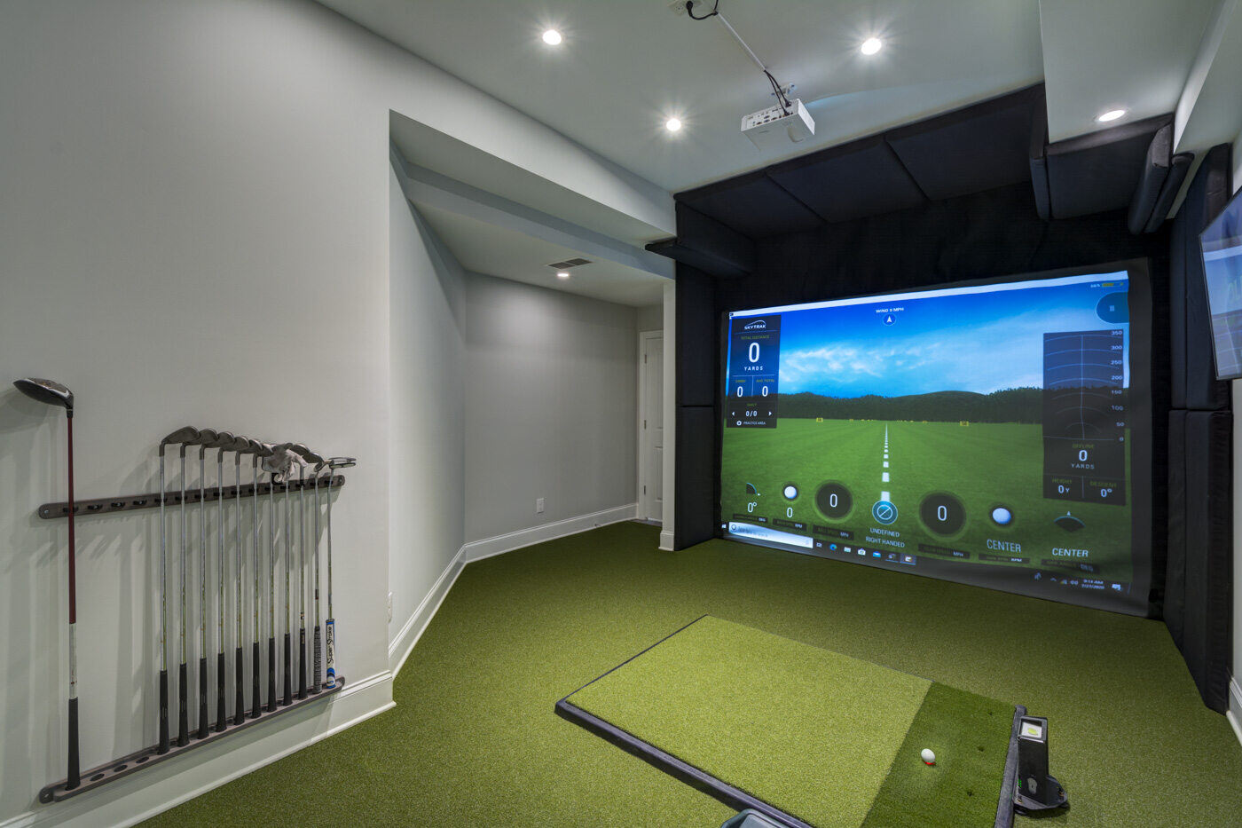 Custom indoor golf simulator room with turf flooring and recessed lighting designed by Silver Oak Remodel in Atlanta, GA