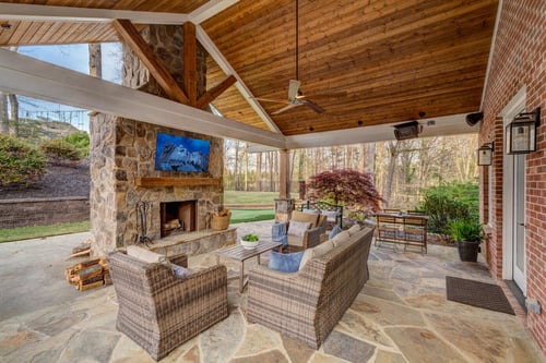 Rustic outdoor lounge with vaulted wood ceiling and stone accents built by Silver Oak Remodeling in Atlant
