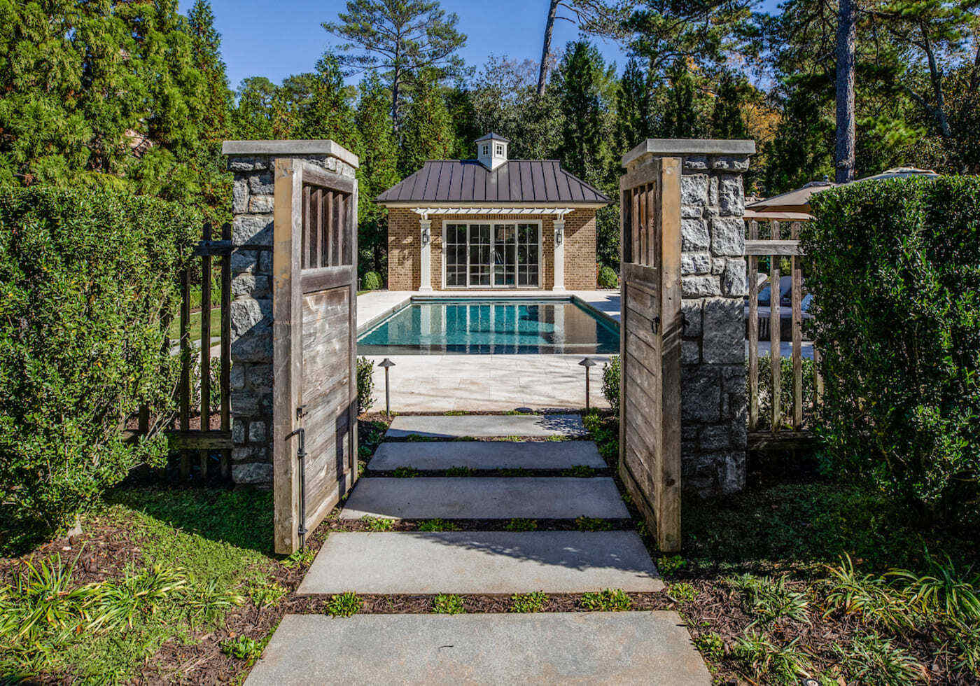 Custom home backyard with pool view through rustic wood gate by Silver Oak Remodeling in Atlanta