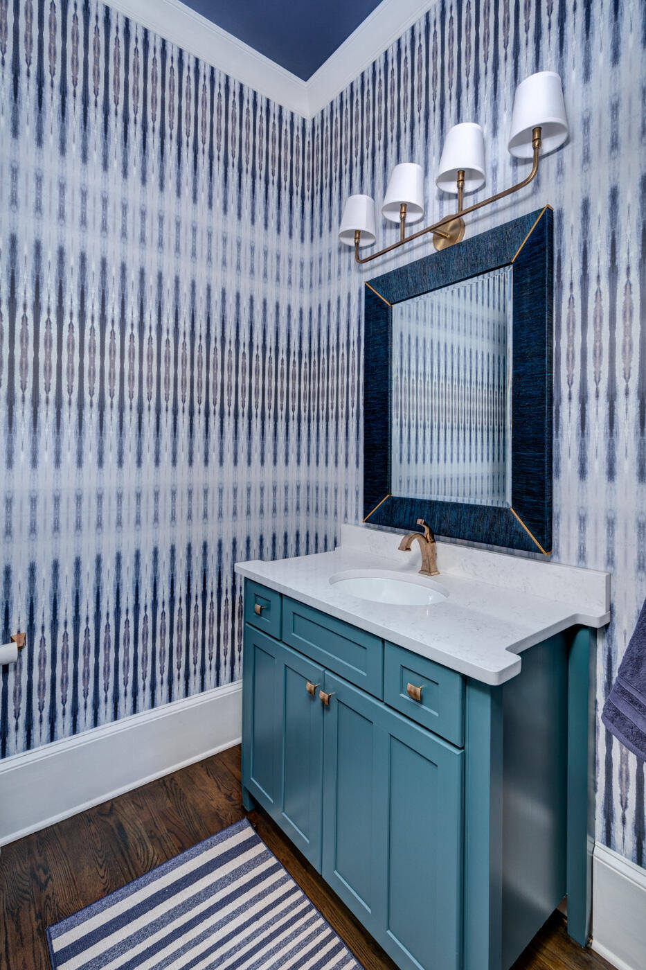 Bold powder room with patterned wallpaper and teal vanity by Silver Oak Remodel in Atlanta, GA