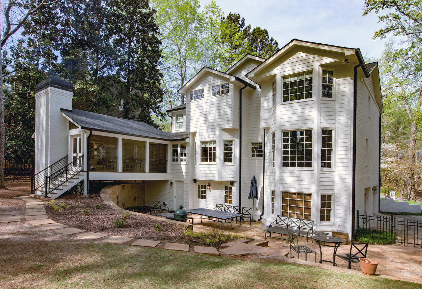 Custom-built white siding home with large windows and stone patio by Silver Oak Remodeling in Atlan
