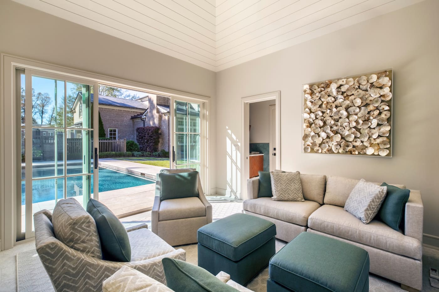 Light-filled sitting area with sliding glass doors opening to a pool in custom Atlanta home by Silv