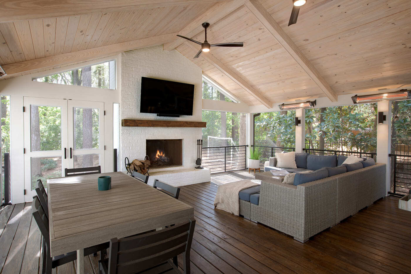 Screened-in porch featuring a cozy seating area and white brick fireplace in a Silver Oak Remodelin