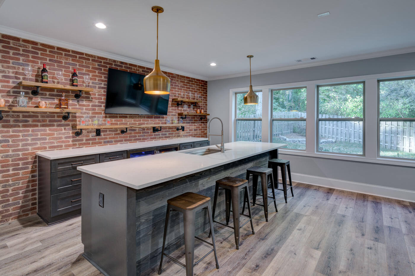 Basement bar renovation in Atlanta, GA featuring exposed brick, wood shelving, and a large island by Silver Oak Remodel